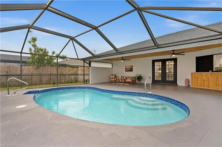 View of pool featuring glass enclosure, ceiling fan, french doors, and a patio area