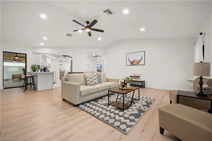 Living room featuring ceiling fan, light wood-type flooring, and vaulted ceiling