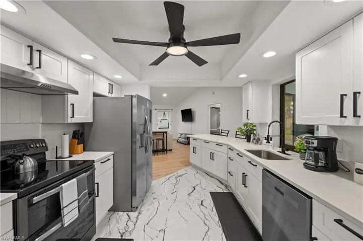 Kitchen featuring light wood-type flooring, stainless steel appliances, ceiling fan, sink, and white cabinets