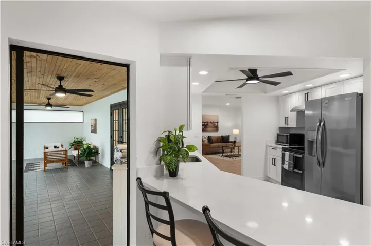 Kitchen featuring kitchen peninsula, stainless steel appliances, ceiling fan, wooden ceiling, and white cabinetry
