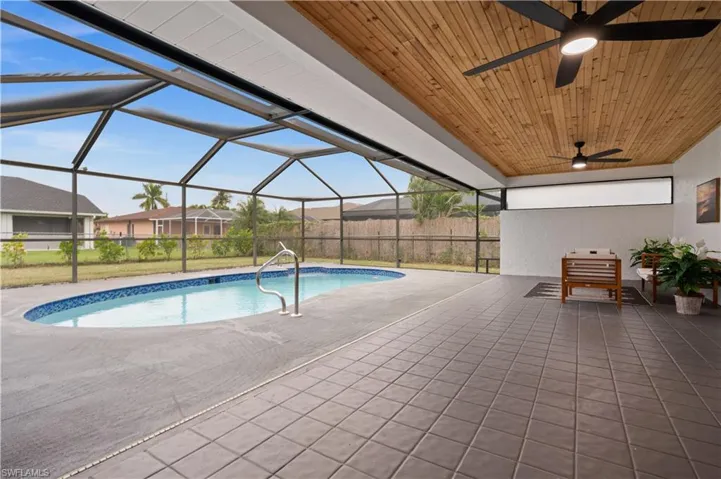View of pool with a lanai, a patio area, and ceiling fan