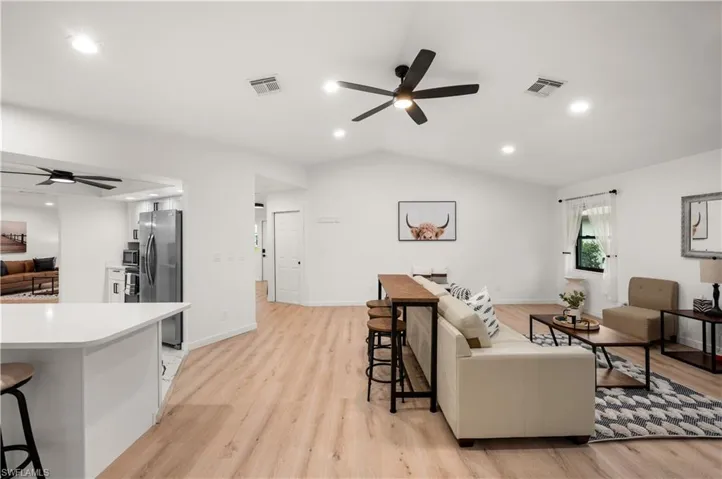 Living room with light hardwood / wood-style floors, ceiling fan, and lofted ceiling
