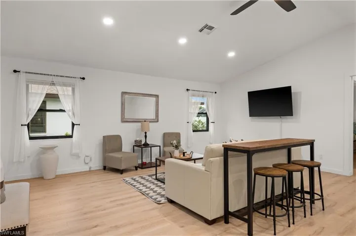 Living room with ceiling fan, light wood-type flooring, and lofted ceiling