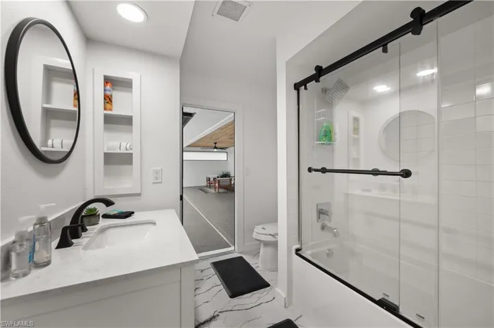 Full bathroom featuring vanity, toilet, and bath / shower combo with glass door