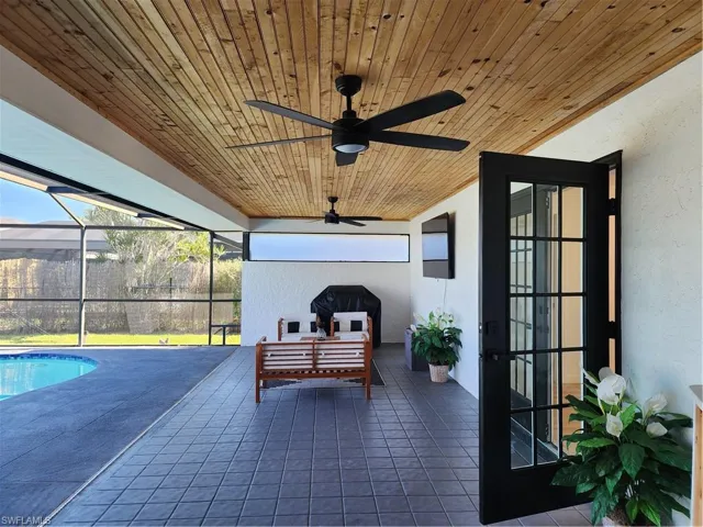Sunroom with ceiling fan, wooden ceiling, and a swimming pool