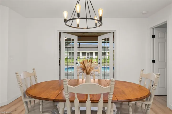 Dining area with light hardwood / wood-style floors and a notable chandelier