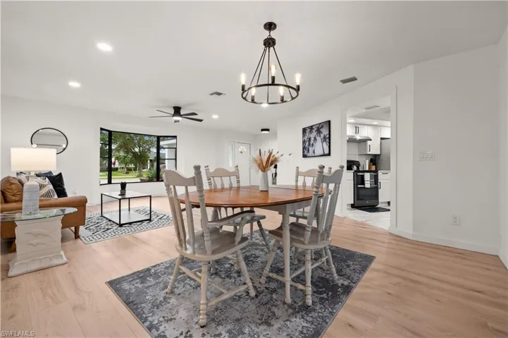 Dining space featuring ceiling fan with notable chandelier and light hardwood / wood-style flooring