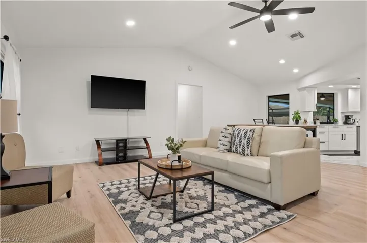 Living room featuring ceiling fan, vaulted ceiling, and light hardwood / wood-style flooring