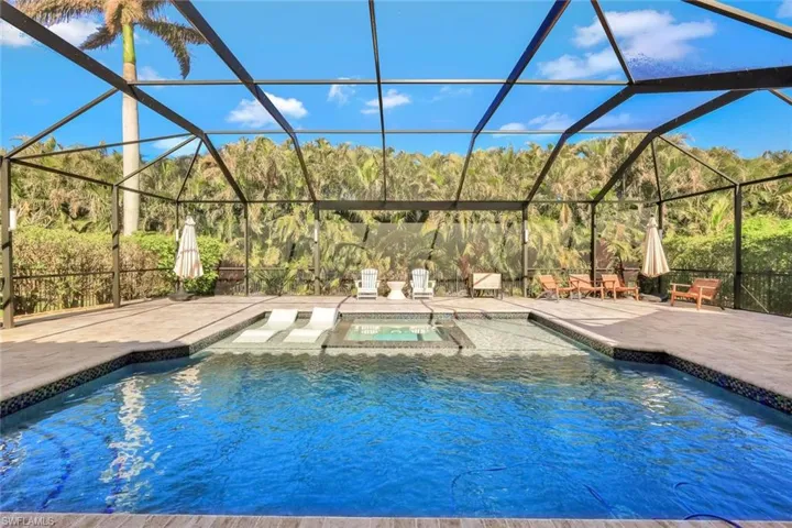 View of swimming pool featuring a lanai, a patio area, and an in ground hot tub