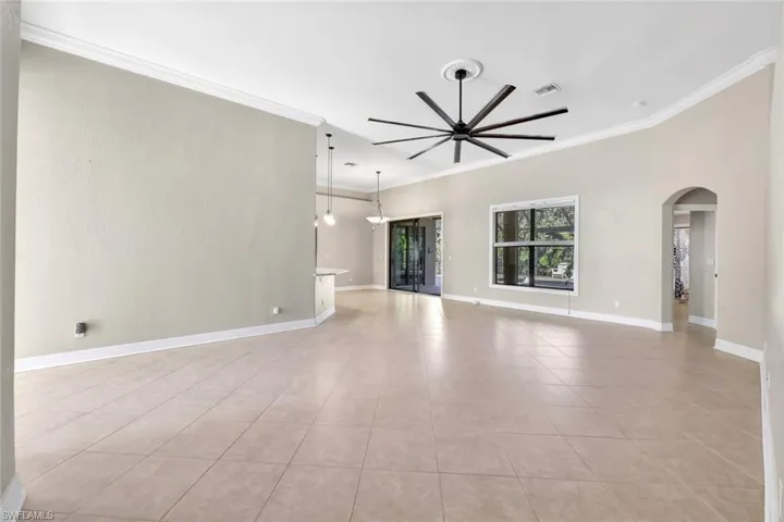 Unfurnished living room featuring crown molding, ceiling fan, and light tile patterned floors