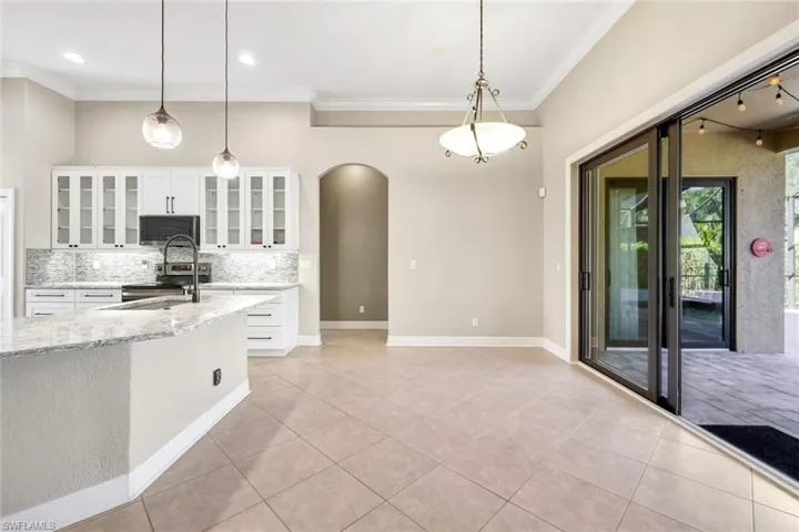 Kitchen with light stone countertops, white cabinetry, tasteful backsplash, pendant lighting, and appliances with stainless steel finishes