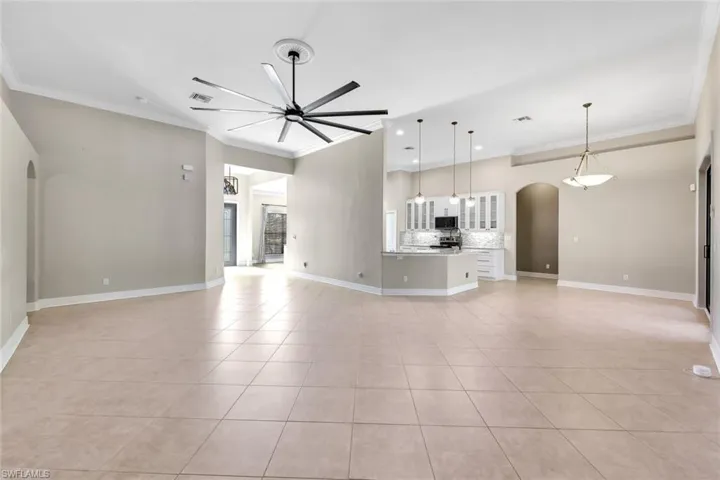 Unfurnished living room featuring ceiling fan, light tile patterned floors, and crown molding