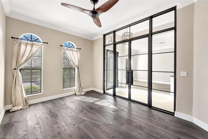 Den featuring plenty of natural light, ceiling fan, ornamental molding, vinyl plank flooring