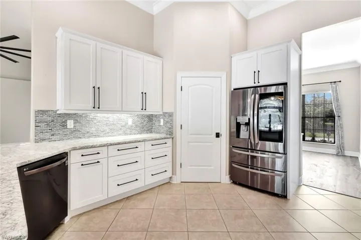 Kitchen with dishwasher, white cabinets, ceiling fan, ornamental molding, and stainless steel fridge with ice dispenser