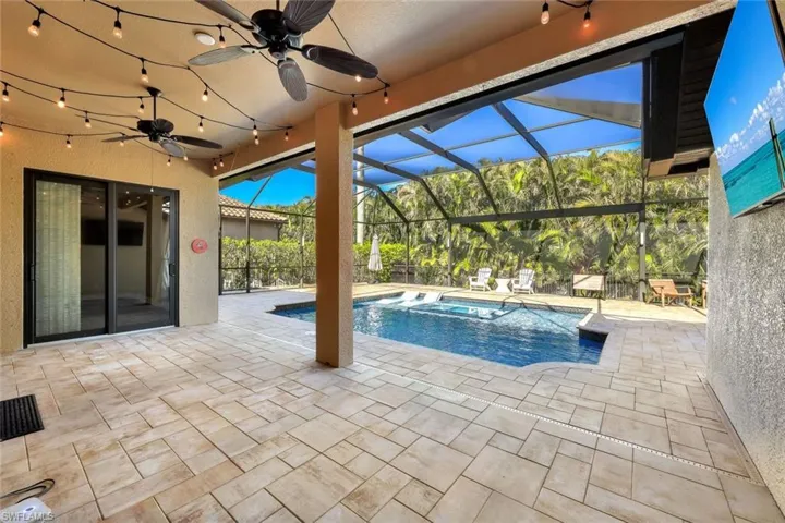 View of swimming pool with a patio area, ceiling fan, and a lanai
