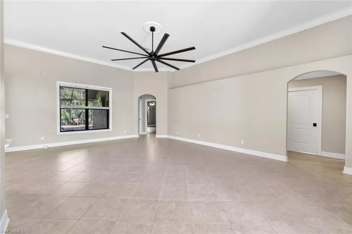 Living room featuring ceiling fan, light tile patterned flooring, and ornamental molding