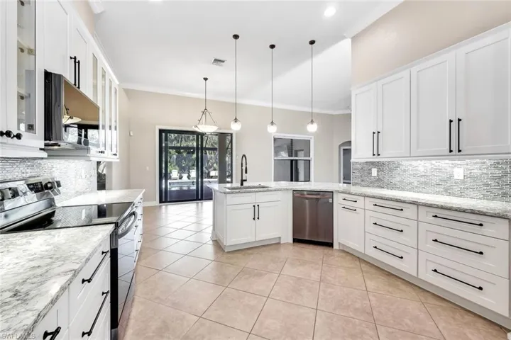 Kitchen with pendant lighting, sink, ornamental molding, appliances with stainless steel finishes, and white cabinetry