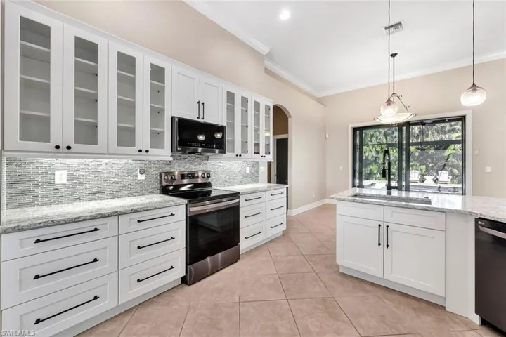 Kitchen with appliances with stainless steel finishes, tasteful backsplash, sink, white cabinetry, and hanging light fixtures