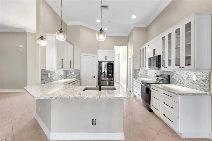Kitchen featuring kitchen peninsula, stainless steel appliances, crown molding, white cabinetry, and hanging light fixtures