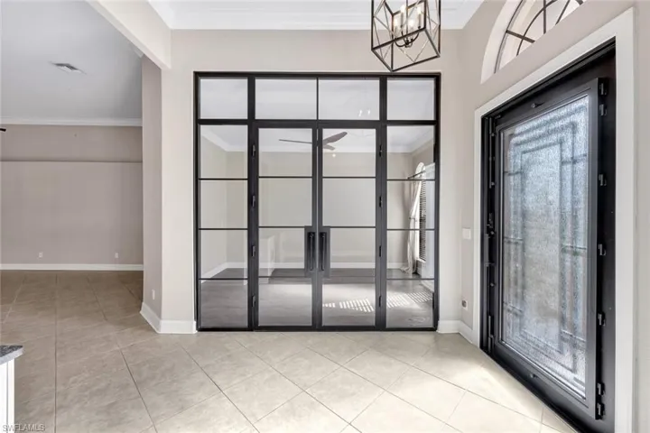 Foyer featuring chandelier, light tile patterned floors, and crown molding