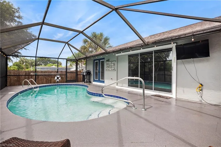 View of swimming pool featuring a patio area, glass enclosure, and a grill