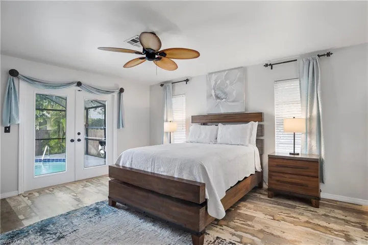 Bedroom with french doors, multiple windows, wood-type flooring, and ceiling fan