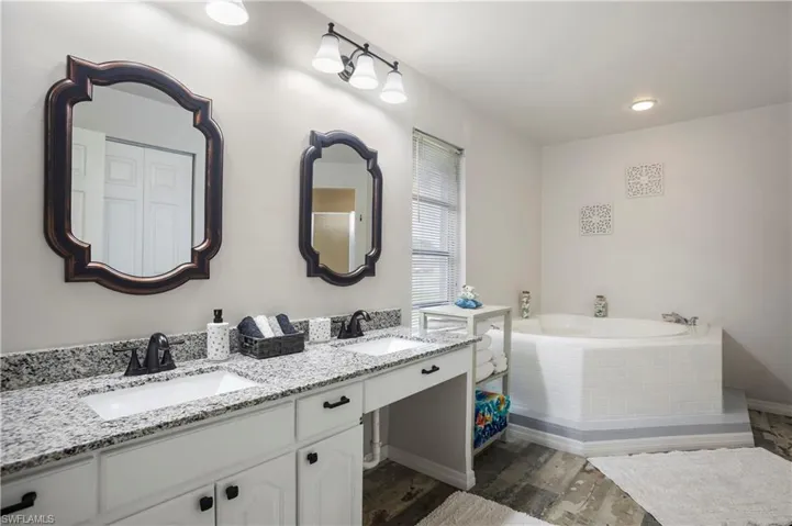 Bathroom with vanity, wood-type flooring, and tiled bath