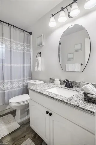 Bathroom with vanity, toilet, a shower with curtain, and hardwood / wood-style floors