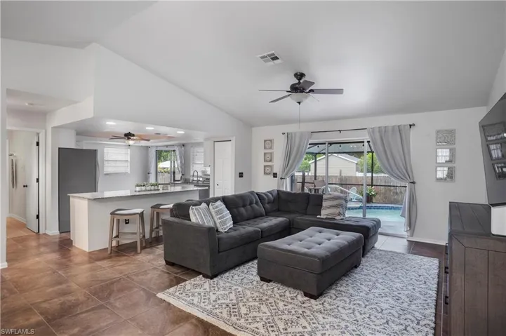 Tiled living room featuring high vaulted ceiling, a healthy amount of sunlight, and ceiling fan