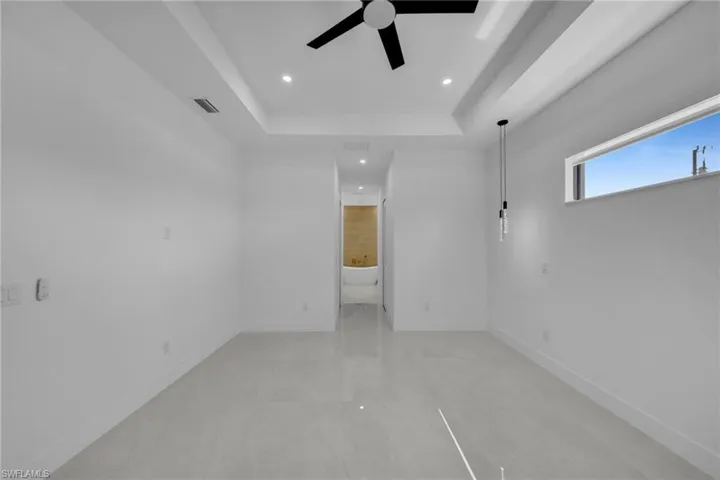 Empty room with recessed lighting, a ceiling fan, visible vents, and a tray ceiling