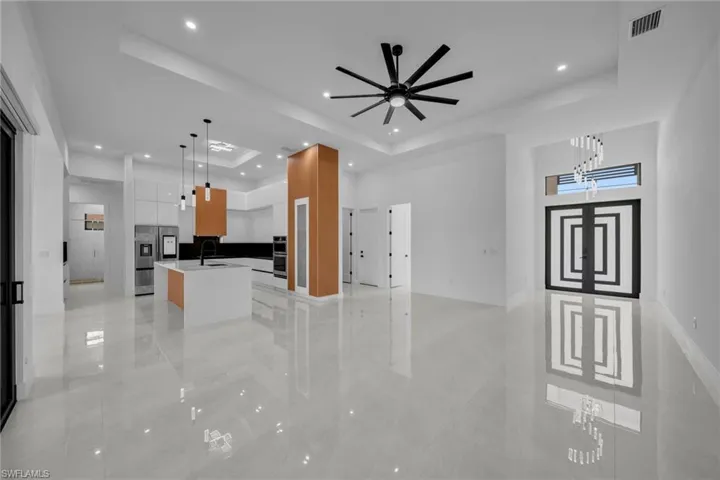 Unfurnished living room featuring a raised ceiling, recessed lighting, visible vents, and baseboards