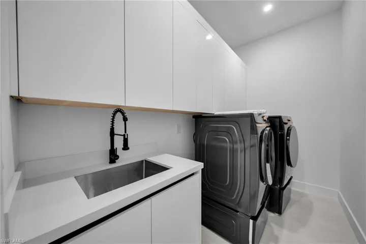 Laundry area featuring a sink, baseboards, recessed lighting, washer and clothes dryer, and cabinet space