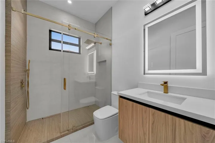 Bathroom with tile patterned floors, a stall shower, toilet, and vanity