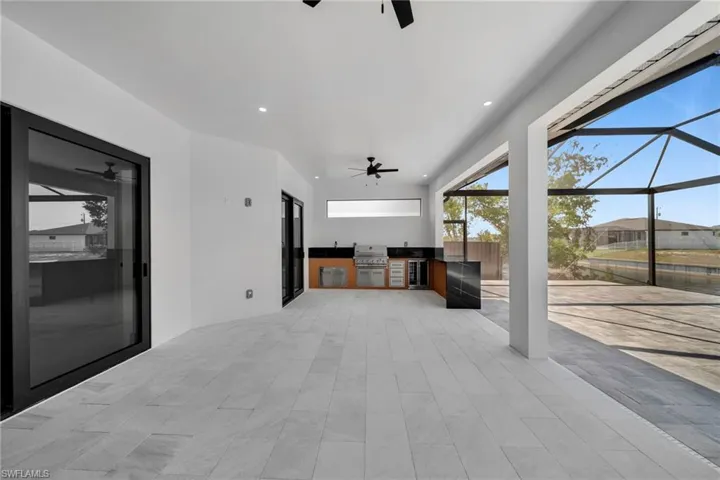 View of patio / terrace featuring area for grilling, a ceiling fan, an outdoor kitchen, and a lanai