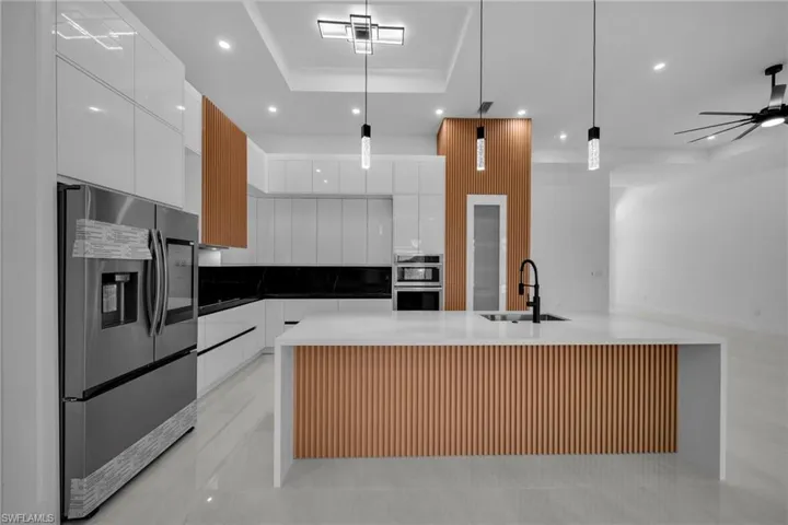 Kitchen featuring a sink, appliances with stainless steel finishes, a tray ceiling, recessed lighting, and modern cabinets