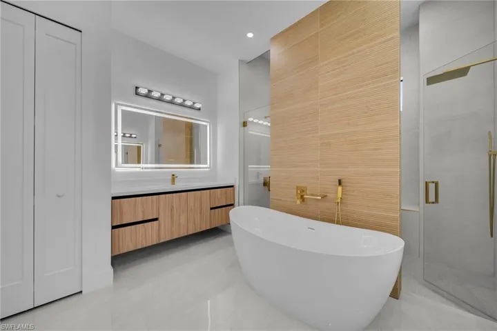 Full bath featuring recessed lighting, a shower stall, tile walls, a freestanding tub, and vanity