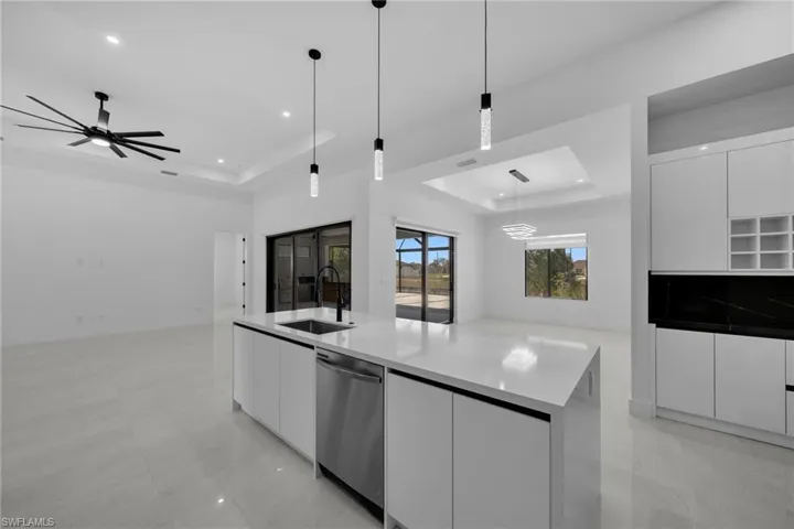 Kitchen featuring modern cabinets, dishwasher, a tray ceiling, and a sink