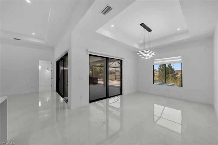 Unfurnished room featuring visible vents, a raised ceiling, plenty of natural light, and recessed lighting