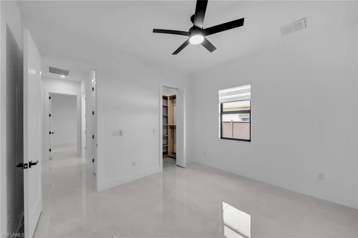 Unfurnished bedroom with a walk in closet, visible vents, and baseboards