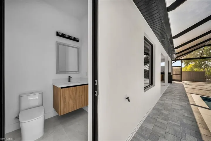 View of side of home with fence, a sink, stucco siding, and a patio area