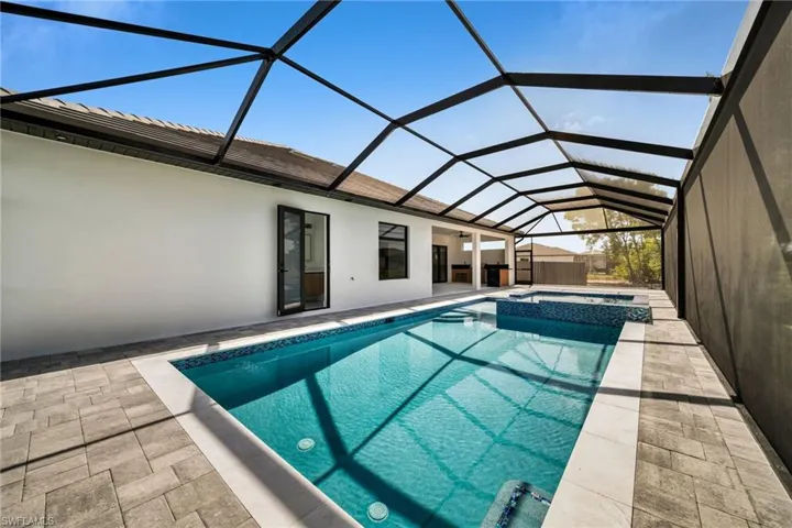 View of pool featuring a lanai, a pool with connected hot tub, and a patio area