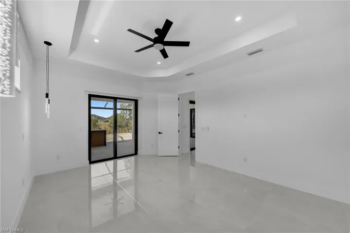 Empty room featuring recessed lighting, a ceiling fan, visible vents, and a tray ceiling