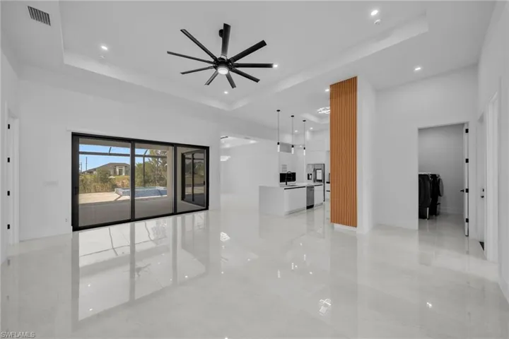 Unfurnished living room featuring recessed lighting, visible vents, ceiling fan, and a raised ceiling
