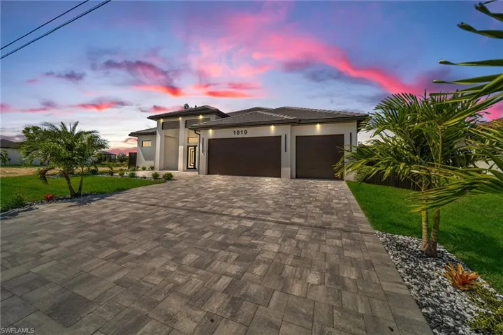 Prairie-style house with stucco siding, decorative driveway, a yard, and an attached garage
