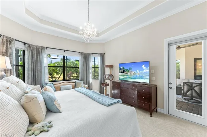 Carpeted bedroom featuring ornamental molding, suspended lighting, access to outside, and a tray ceiling
