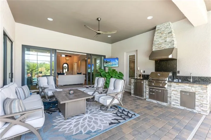 View of patio featuring a ceiling fan, an outdoor kitchen and area to lounge, and a fire pit
