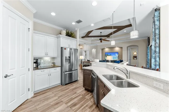 Kitchen featuring arched walkways, stainless steel appliances, hanging light fixtures, a ceiling fan, and ornamental molding