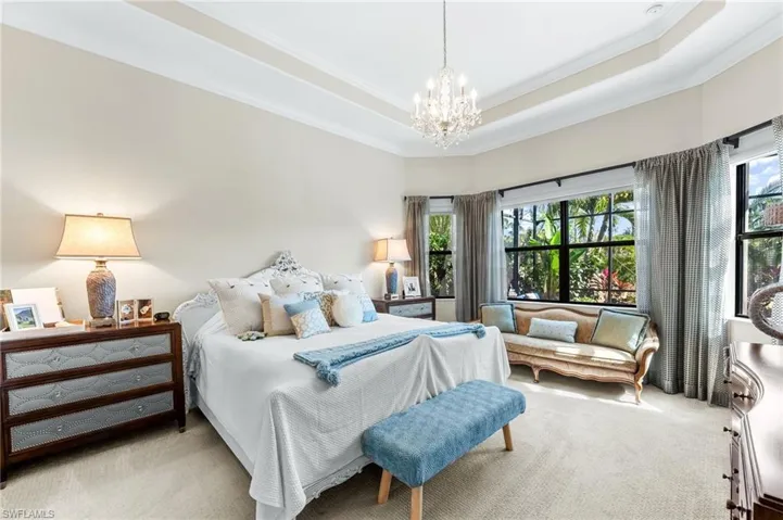 Carpeted bedroom featuring suspended lighting, a tray ceiling, and crown molding