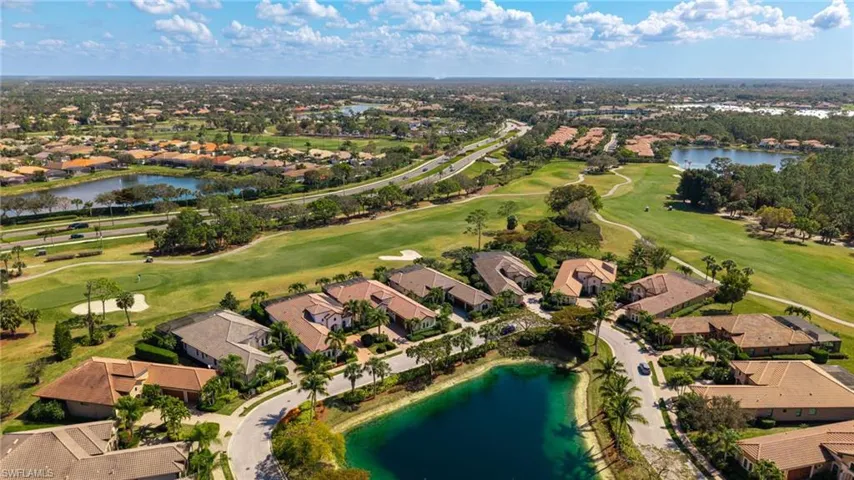 Aerial perspective of suburban area featuring a nearby body of water and a local golf course