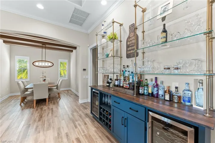Bar featuring butcher block countertops, open shelves, blue cabinetry, wood finish floors, and beverage cooler